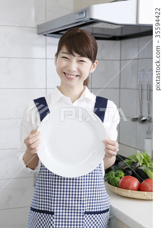 Woman in apron dress with white plate Woman in apron dress with white plate 35594422