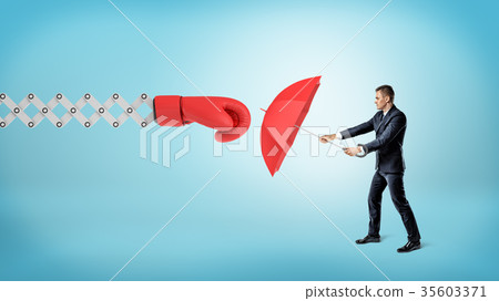 A small businessman holding a red umbrella to hide 35603371
