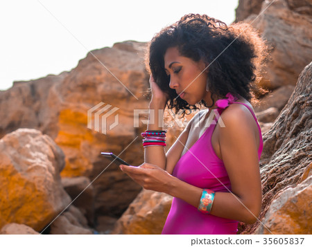 afro girl reading e-book on tropical rocks beach 35605837