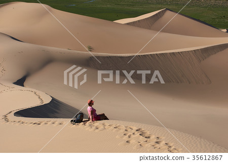 Relaxed tourist sitting on sand dunes in desert 35612867