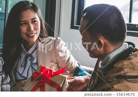 Young man is giving a present to girlfriend Young man is giving a present to girlfriend 35614670