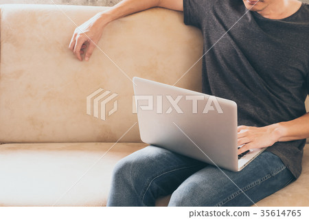 young man sitting on sofa and using a laptop 35614765