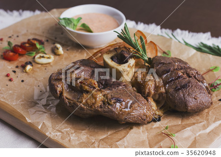 large roasted piece of meat on bone with sauce large roasted piece of meat on bone with sauce 35620948