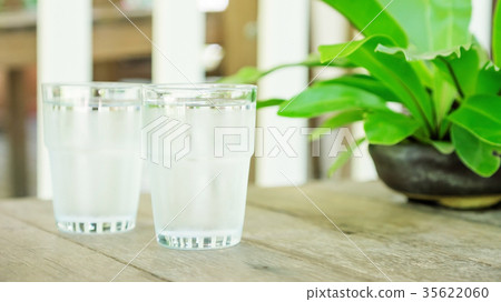 a glass of water on a wooden table. a glass of water on a wooden table. 35622060