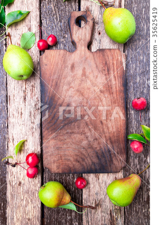 Pear and small apple around empty cutting board Pear and small apple around empty cutting board 35625419