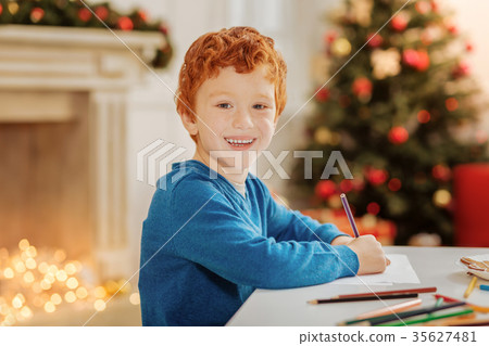 Radiant curly haired child smiling while drawing Radiant curly haired child smiling while drawing 35627481