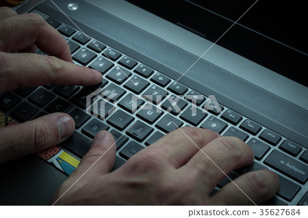 Men's hands are typing on the laptop's keyboard 35627684