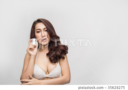 Beautiful girl in swimwear is applying sunscreen. 35628275