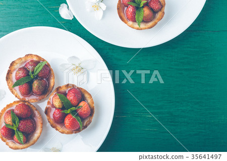 Strawberry tartlet on white plates on green Strawberry tartlet on white plates on green 35641497