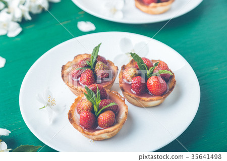 Strawberry tartlet on white plates on green Strawberry tartlet on white plates on green 35641498