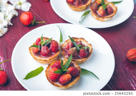 Strawberry tartlet on white plates on red Strawberry tartlet on white plates on red 35643293