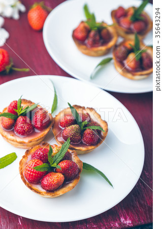 Strawberry tartlet on white plates on  red 35643294