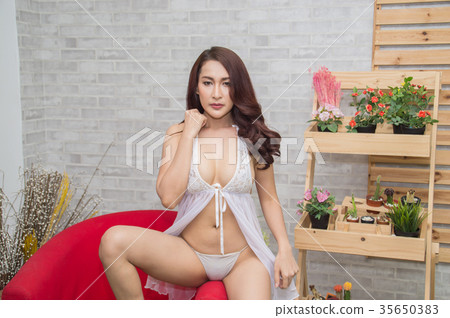 Woman in sexy dress white poses in bedroom. Woman in sexy dress white poses in bedroom. 35650383