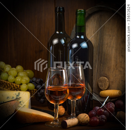 Glasses of rose wine cheeses grapesand barrel on brown wooden background 35651624