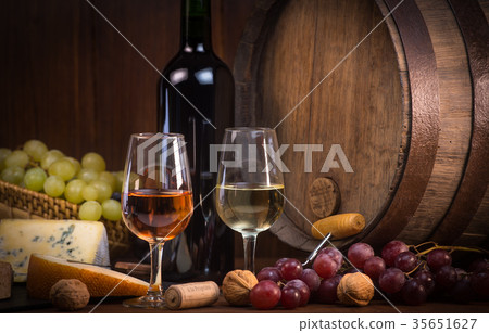 Glasses of rose and white wine cheeses grapesand barrel brown background 35651627