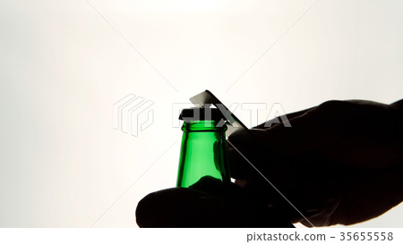 Silhouette of Male hands opening green beer bottle 35655558