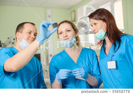 Male dentist showing x-ray to female assistant at dental clinic Male dentist showing x-ray to female assistant at dental clinic 35658778