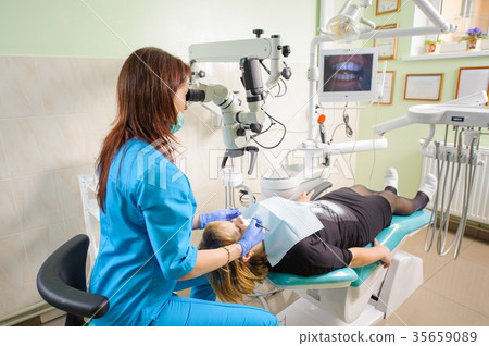 Female dentist working with microscope at modern dentist clinic Female dentist working with microscope at modern dentist clinic 35659089