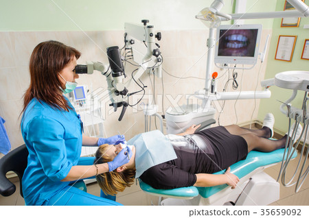 Female dentist working with microscope at modern dentist clinic Female dentist working with microscope at modern dentist clinic 35659092
