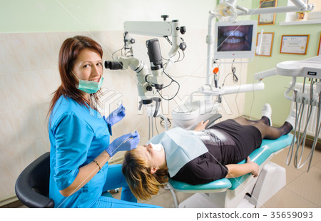 Female dentist working with microscope at modern dentist clinic Female dentist working with microscope at modern dentist clinic 35659093