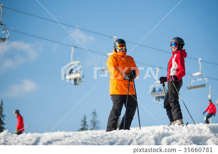 Man and woman skiers with skis at winter resort 35660781