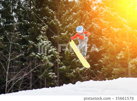 Boy jumping and keeps one hand on the snowboard Boy jumping and keeps one hand on the snowboard 35661578