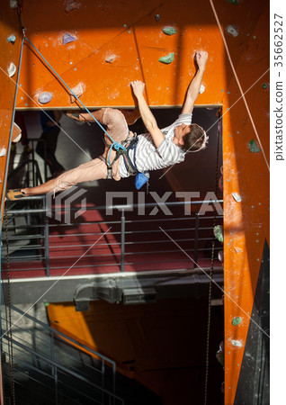 Male rock-climber practicing climbing on rock wall indoors 35662527