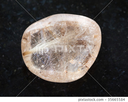 tumbled Rutilated Quartz gemstone on dark 35665584