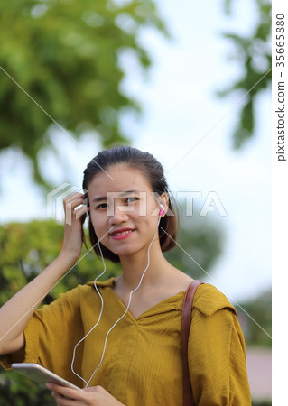 A woman listening to music on a smartphone 35665880