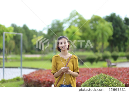 A woman listening to music on a smartphone 35665881