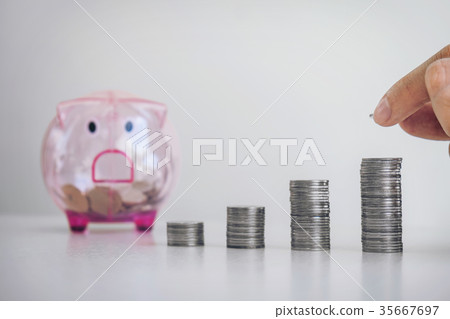 Businessman putting coins increase growth at a desk and a piggy Businessman putting coins increase growth at a desk and a piggy 35667697
