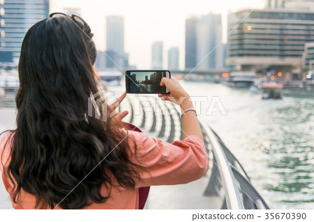Tourist taking picture of Dubai marina with smart phone 35670390