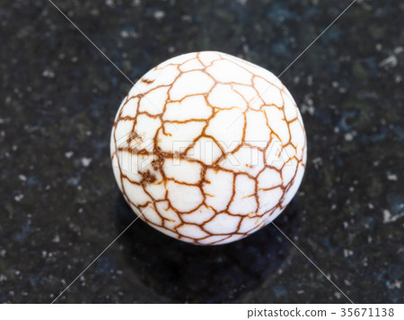 bead from cracked Cacholong gemstone on dark 35671138
