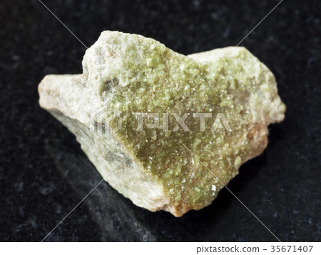 green Vesuvianite crystals on rough stone on dark 35671407