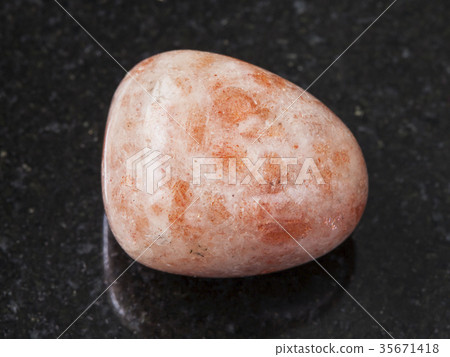 polished sunstone (heliolite) gem stone on dark 35671418