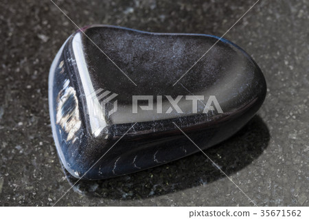 tumbled hawk-eye gemstone on dark background 35671562