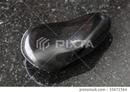 tumbled black obsidian gemstone on dark 35671564