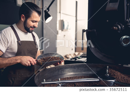 Happy man keeping spatula with coffee beans 35672511