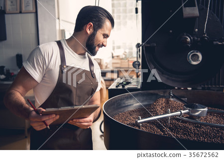 Cheerful glad man writing about roasting beans 35672562