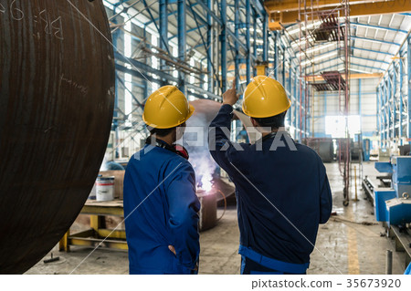 Two Asian experts talking while supervising 35673920