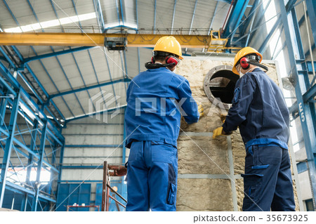 Workers applying insulation material to an Workers applying insulation material to an 35673925