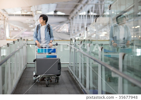 young asian man walking with trolley in airport 35677948