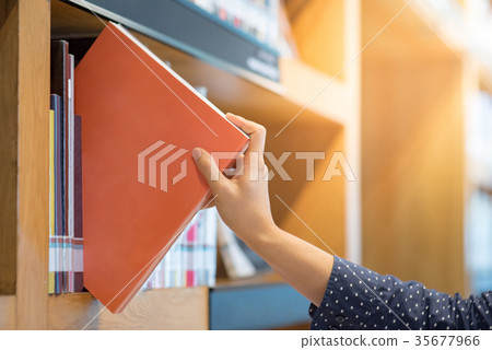 male hand picking orange book in library 35677966