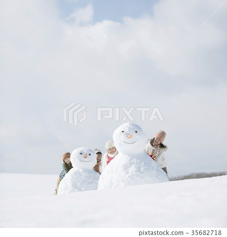 Elementary school student putting his face from behind a snowman Elementary school student putting his face from behind a snowman 35682718