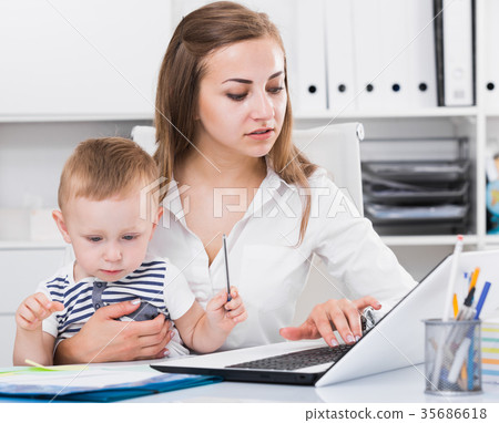 Mother with kid is working behind laptop Mother with kid is working behind laptop 35686618