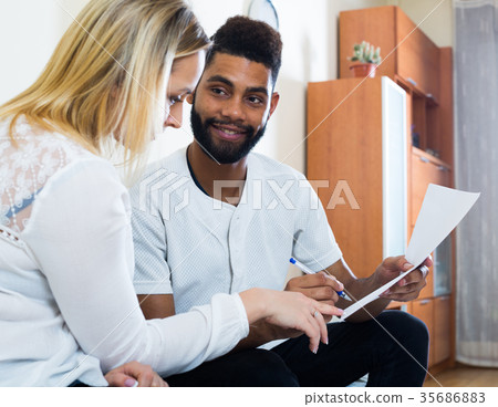 Interracial couple discussing banking offer for mortgage at home 35686883