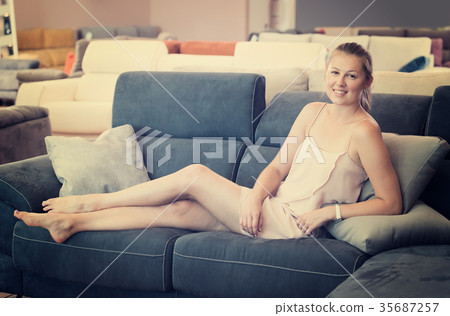 Young female customer barefoot choosing sofa Young female customer barefoot choosing sofa 35687257