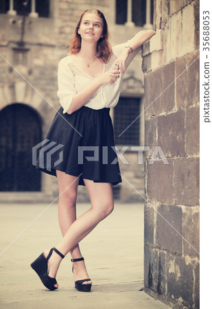 Positive young girl standing near the stone wall 35688053