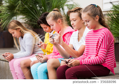 Five kidsare chatting on their smartphone Five kidsare chatting on their smartphone 35688096