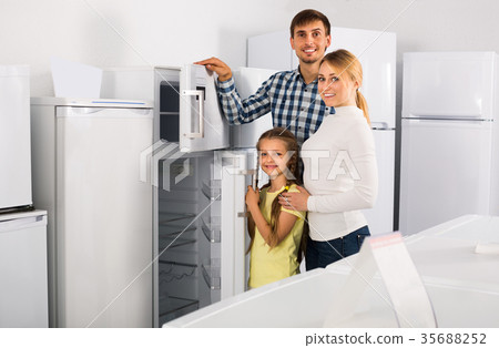 Man and woman with child buying refrigerator Man and woman with child buying refrigerator 35688252
